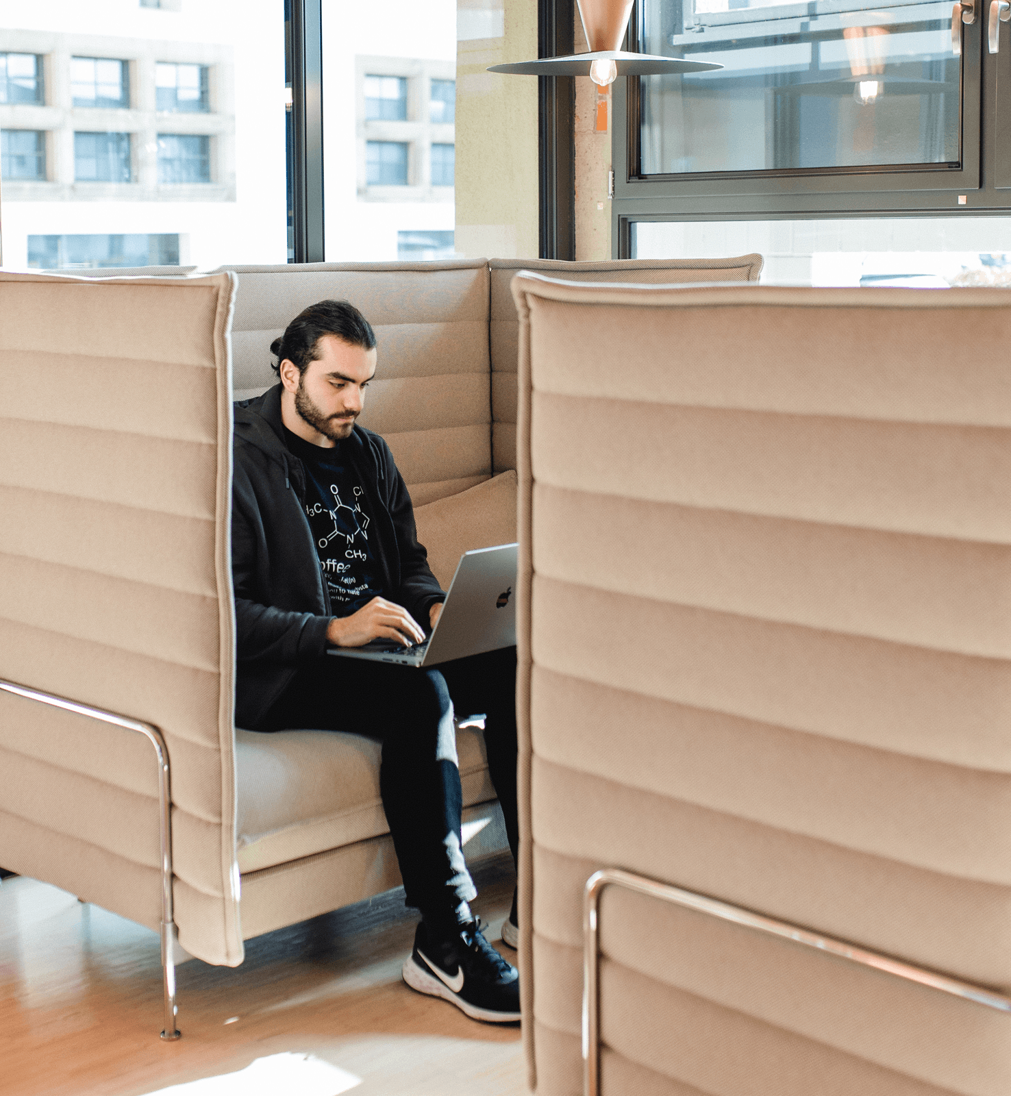 Ein Mitarbeiter am Macbook in einer Sitzecke