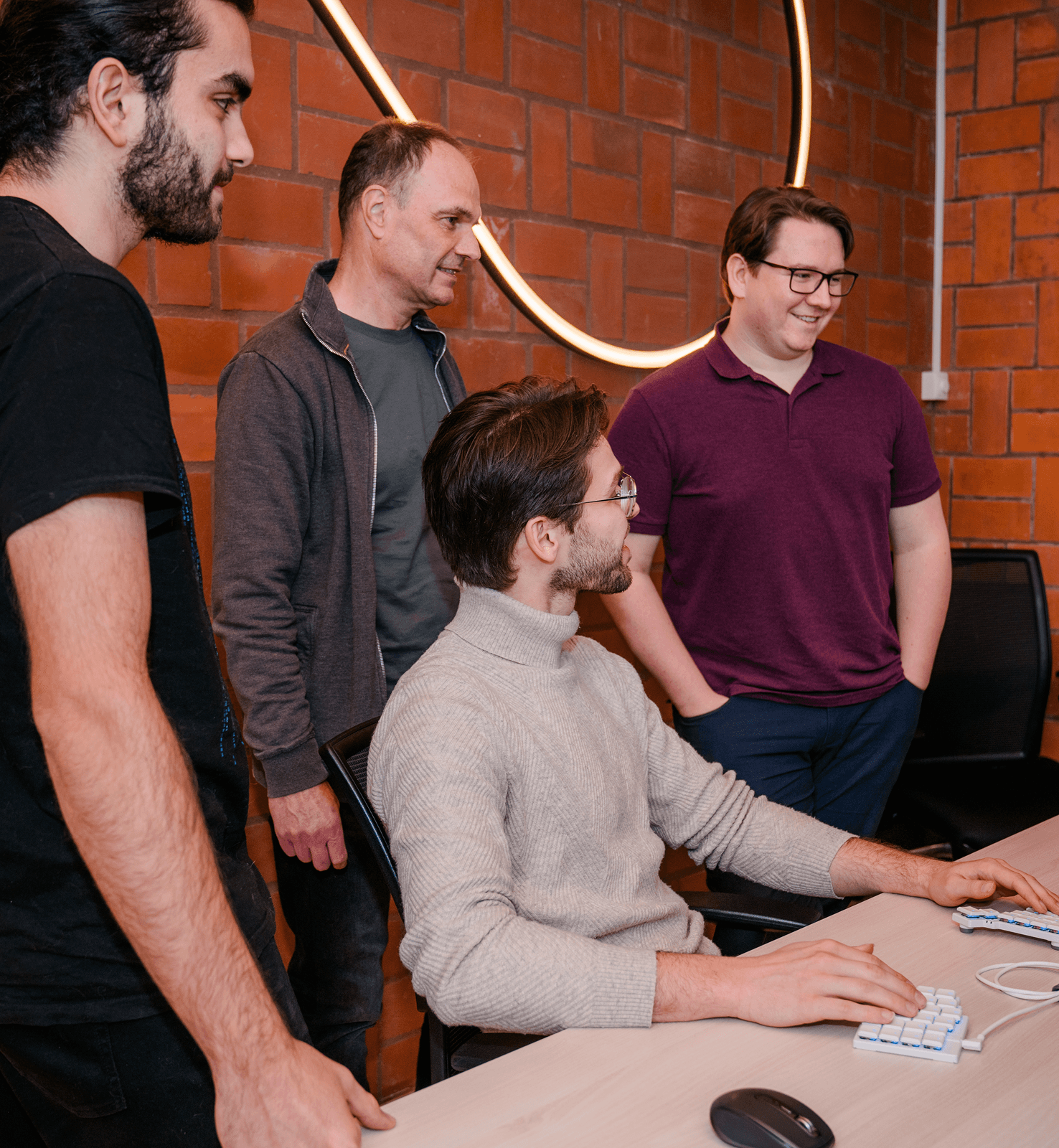 4 Mitarbeiter, davon 3 stehen vor einem PC